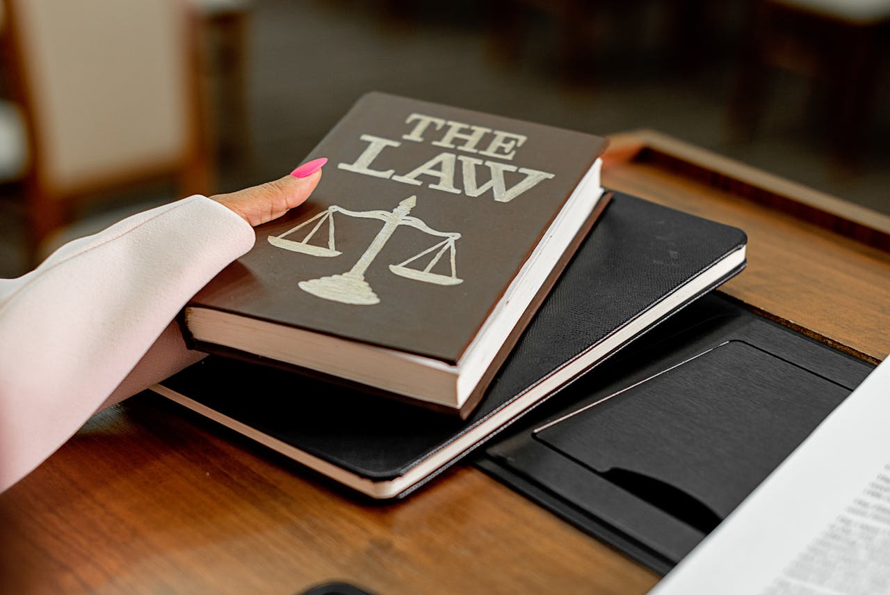 Services Closeup image of a law book titled 'The Law' on a wooden desk with scales of justice.