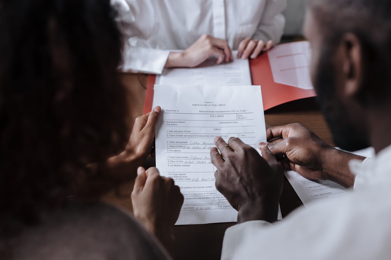 Services A couple collaboratively signs legal documents in the presence of an advisor.